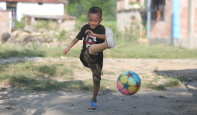 Kleiner lächelnder Junge, der Fußball spielt 