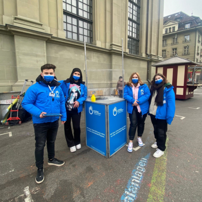 Rednerinnen und Redner der Podiumsdiskussion auf einem langen Tisch vor dem Publikum.