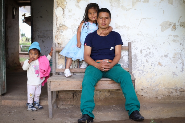 Un père avec ses deux enfants devant sa maison