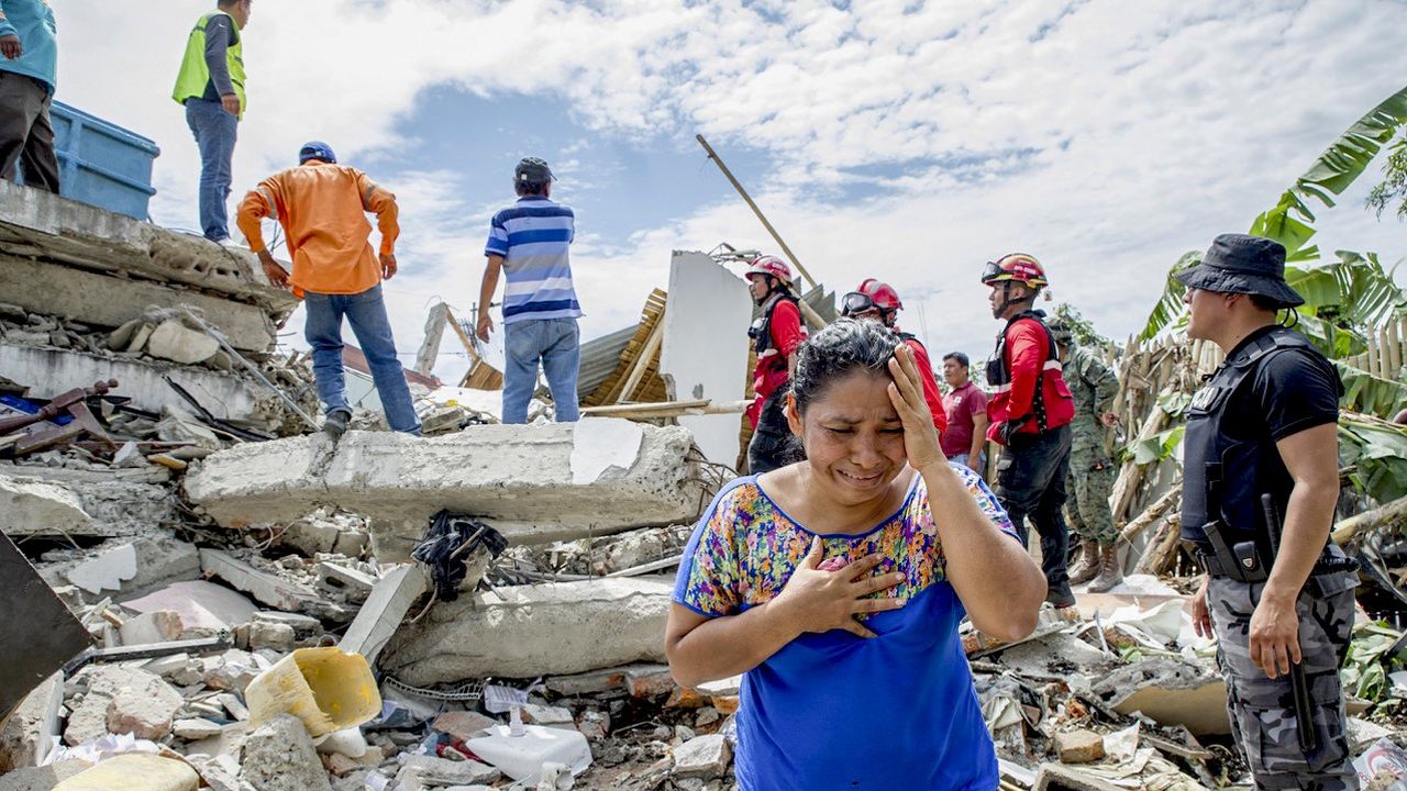 A woman cries as the search and rescue workers on duty over the collapsed buildings in Pedernales, Manabi Province of Ecuador on April 17, 2016. 