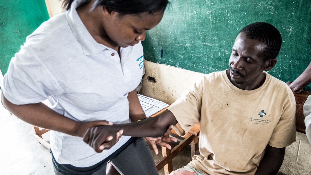 Ein Patient, der beim Erdbeben 2010 verletzt wurde, bei seiner Behandlung mit der Physiotherapeutin von Handicap International