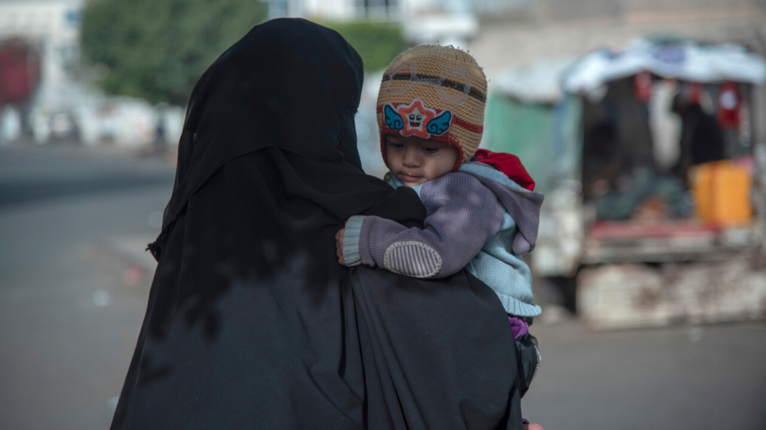Eine Mutter trägt ihr Kind in Sana'a