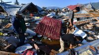 Mehrere Menschen fahren an einem auf Grund gelaufenen Boot und zerstörten Gebäuden in Palu vorbei, nachdem ein Erdbeben und anschließender Tsunami die Stadt am 1. Oktober 2018 traf.