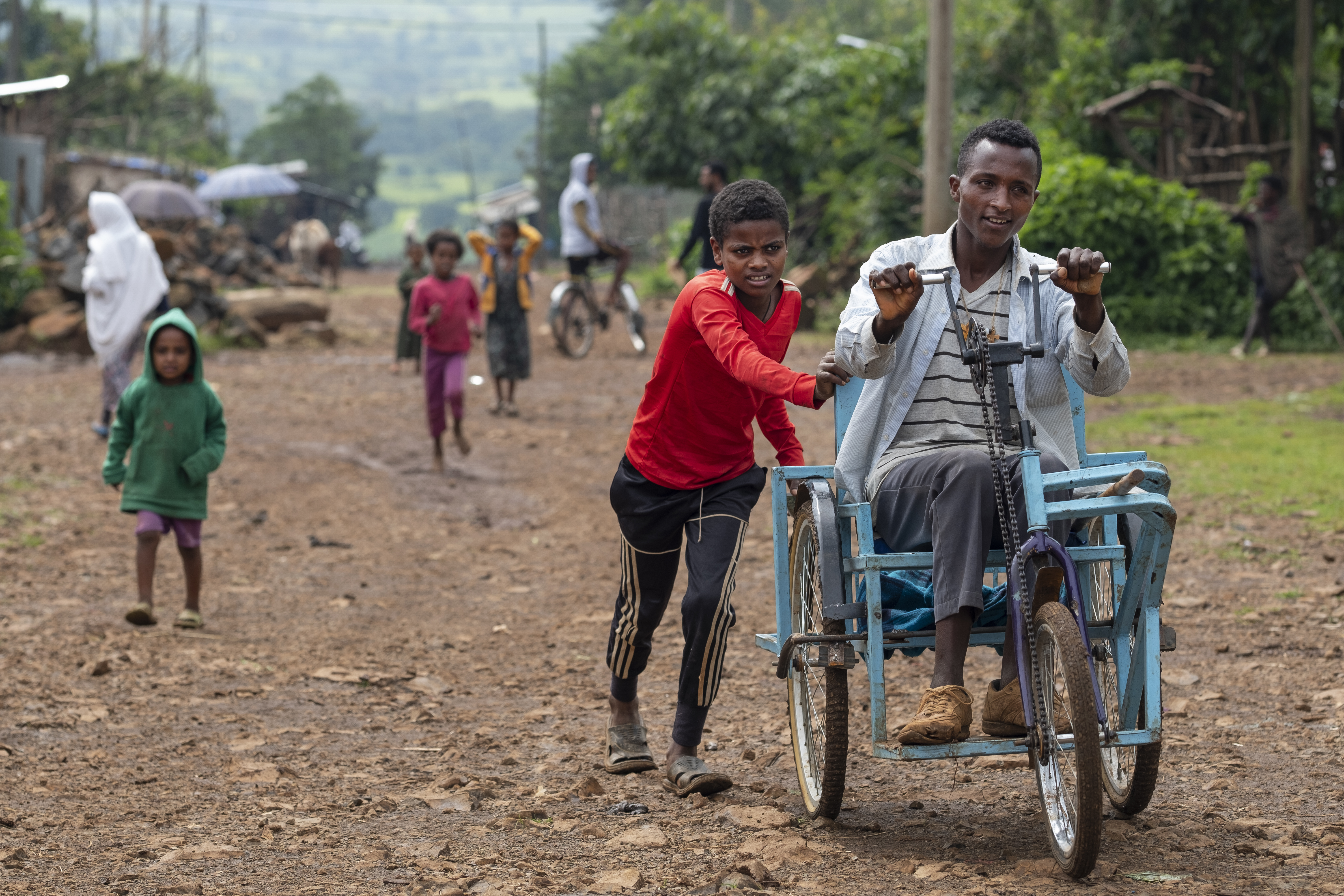 Un enfant qui aide à pousser le chaise roulante d'un homme en situation d'handicap