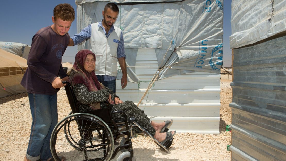 Watfa, une réfugiée syrienne de 80 ans, et son petit fils  comment utiliser la nouvelle chaise roulante offerte par l'association humanitaire Handicap International. 