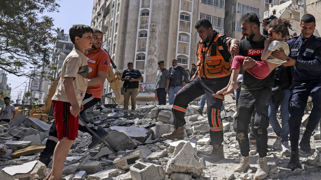 Des Palestiniens évacuent une fillette des décombres d'un immeuble détruit dans le quartier résidentiel de Rimal, dans la ville de Gaza, le 16 mai 2021, après un bombardement israélien massif sur l'enclave contrôlée par le Hamas. 