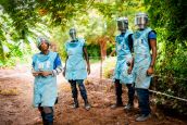 Unser Team iDrei Minenräumer und eine Minenräumerin in Schutzkleidung stehen auf einem Feldweg, umgeben von üppiger Vegetation.m Senegal wartet darauf, mit der Minenräumung zu beginnen