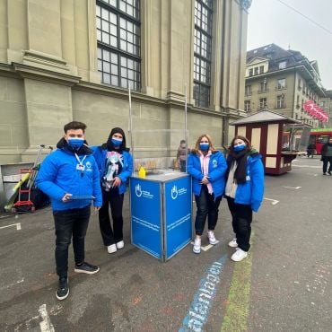 Quatre personnes portant des vestes Handicap International bleues autour d'un stand Handicap International