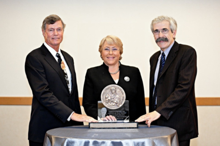 Stehend von links nach rechts: Steven M. Hilton, Präsident und CEO der Hilton Foundation; Michelle Bachelet, die erste Untergeneralsekretärin und Exekutivdirektorin von UN Women und ehemalige Präsidentin von Chile von 2006 bis 2010 und Jean-Baptiste Richardier. 