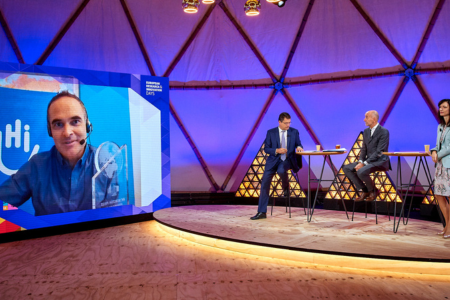 Manuel Patrouillard auf dem Bildschirm bei der Verleihung des EU-Horizon-Preises und 3 Personen auf der Bühne, die rechts sitzen. 