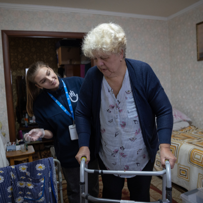 Eine ältere Empfängerin erhält von der Physiotherapeutin HI Maria in Novomoskovsk, Ukraine, Physiotherapie und Mobilitätstraining.