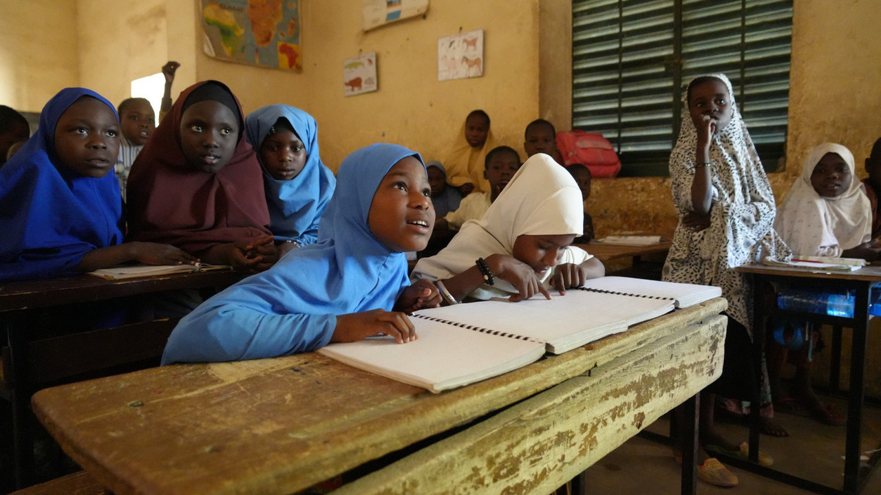 Photo d'une salle de cours dans laquelle une fille assise à une table lève le regard et sourit.