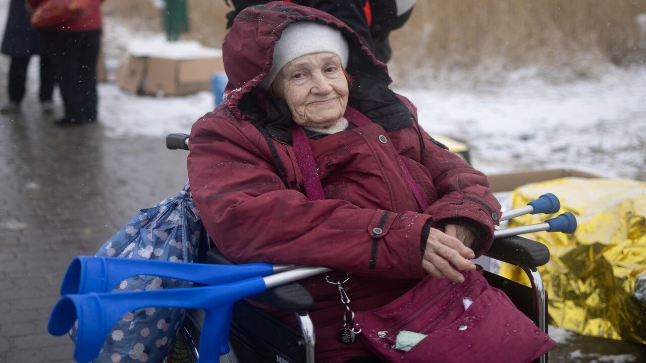 Eine alte Frau im Rollstuhl schaut in die Kamera
