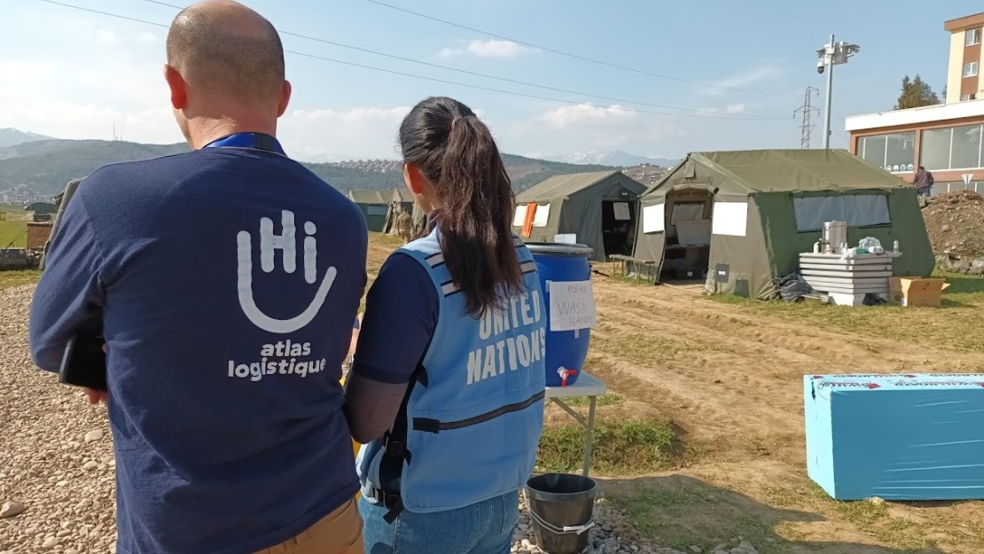 Deux personnes de dos un homme et une femme avec des blousons bleus dont un avec le logo de Handicap International 