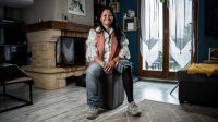 Emilie Pin Vath dans une maison, souriante, assise sur une chaise portant une prothèse à sa jambe gauche