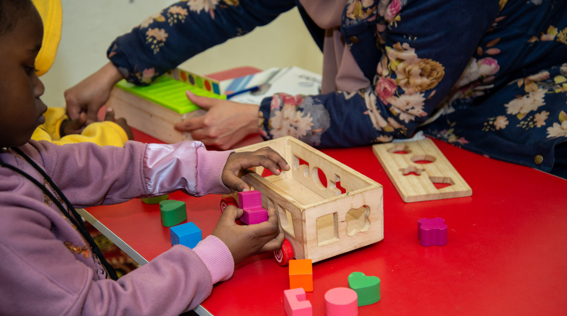 Ein Kind, das mit Puzzles mit farbigen Formen in einer Holzkiste spielt