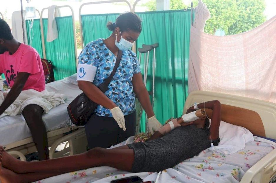 Une physiothérapeute partenaire de HI donne des soins de réadaptation à un patient blessé lors du tremblement de terre. Haïti, 2021.