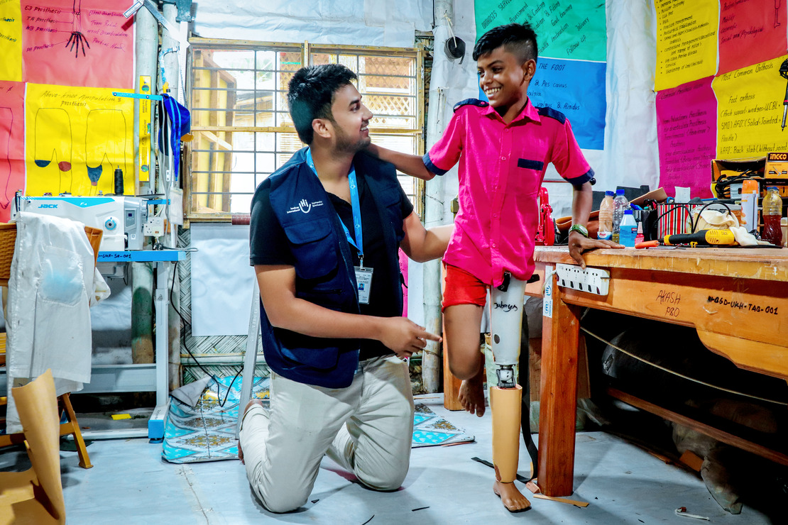 Un garçon portant un t-shirt rose et une prothèse à la jambe gauche se tenant sur l'épaule d'un homme avec un t-shirt bleu
