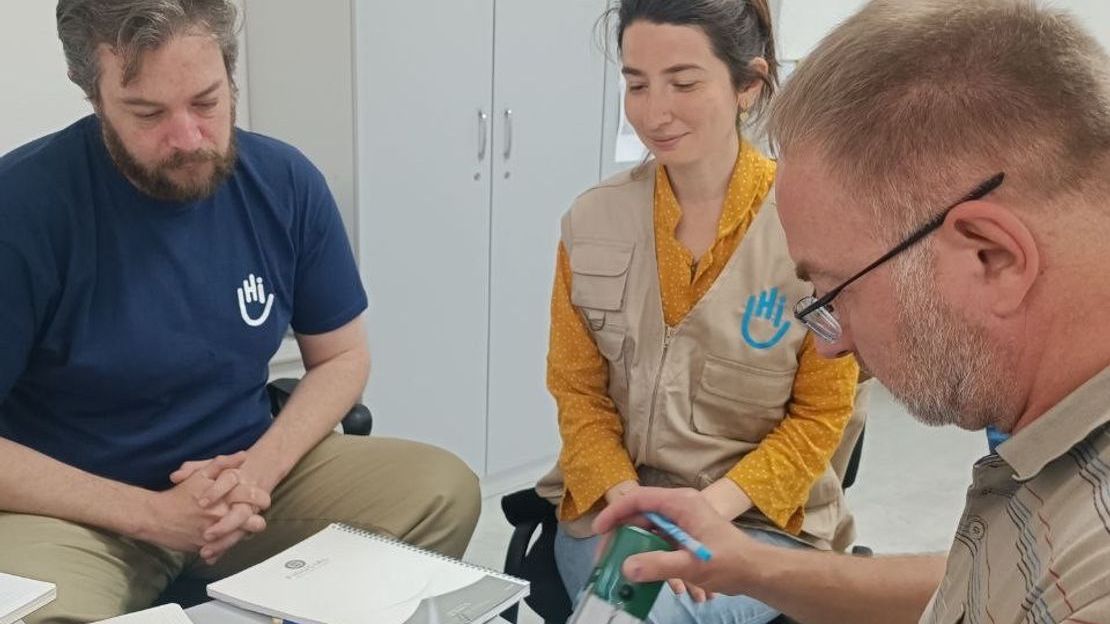 Le personnel de HI, Jeremie (à gauche) et Caglar (à droite) signent l'accord officiel de partenariat avec l'Université de psychologie médicale de Tchernivtsi et l'Organisation psychosociale ukrainienne. 