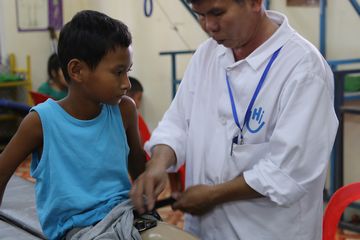 Vimean, kinésithérapeute adapte la prothèse de Sovannareach au centre de Handicap International au Cambodge