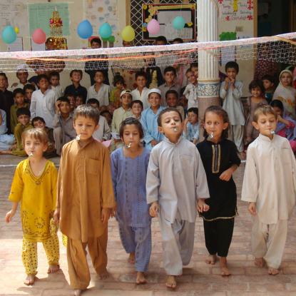 Des jeunes enfants font la fête, des ballons sont accrochés au plafond.