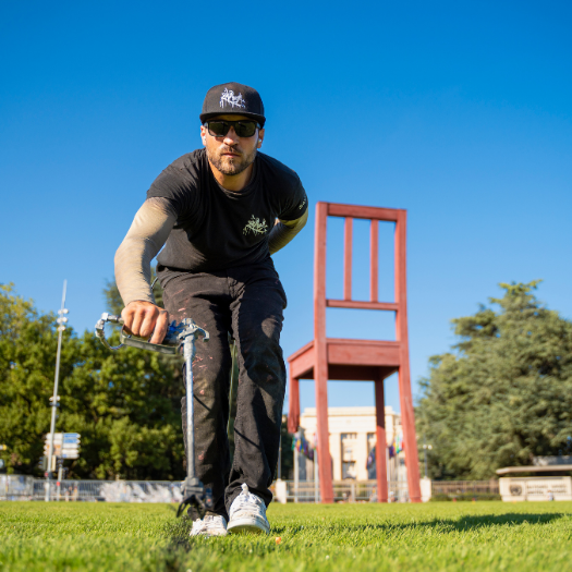 Artist Saype painting in front of Broken Chair