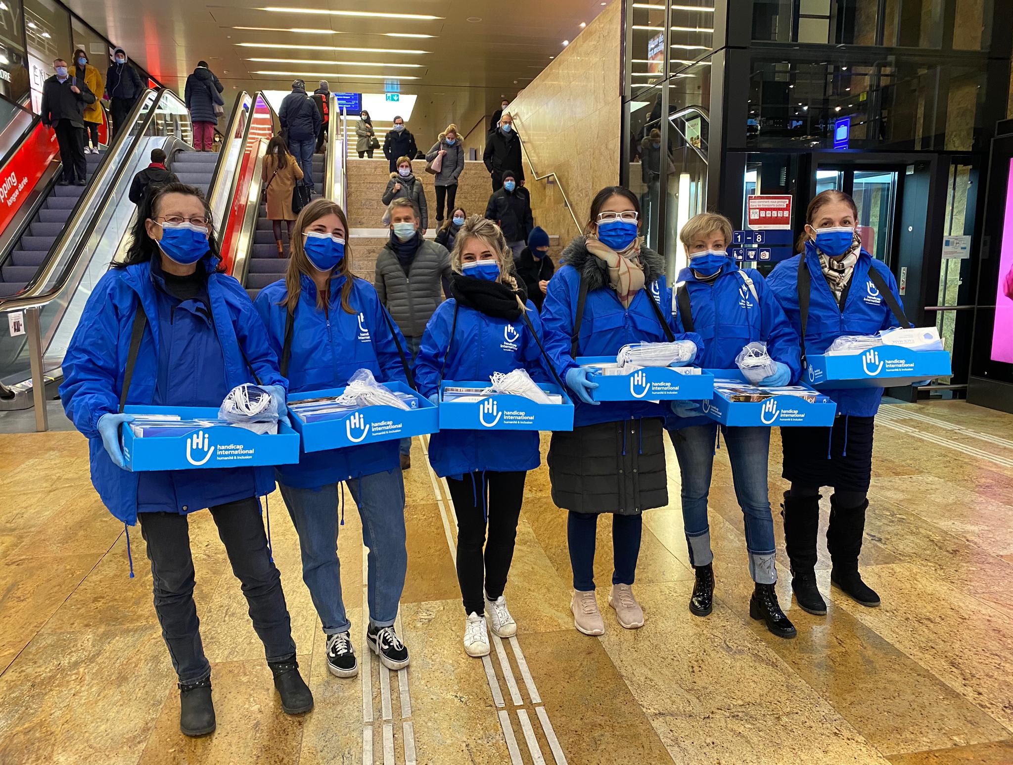 Freiwillige, die am Genfer Bahnhof Masken verteilen